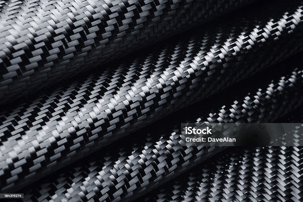 Macro close-up of black carbon fiber weave pattern with glossy highlights, showing layered composite fabric.