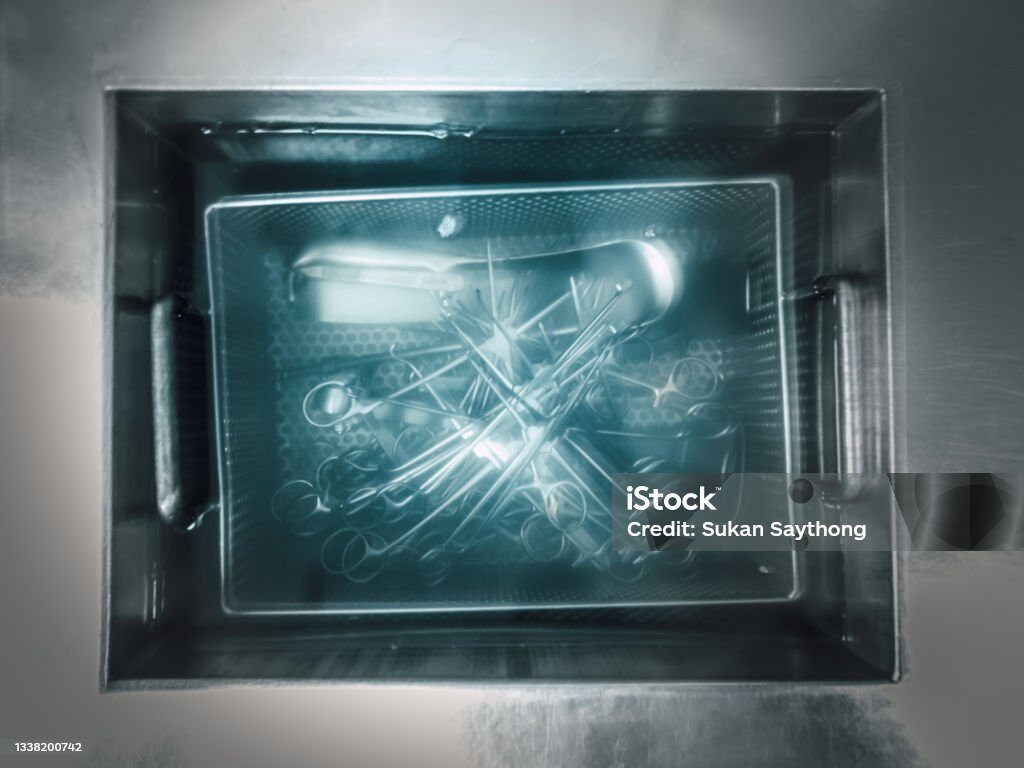 Top view of surgical instruments in a metal tray inside an autoclave sterilizer, ready for medical use.