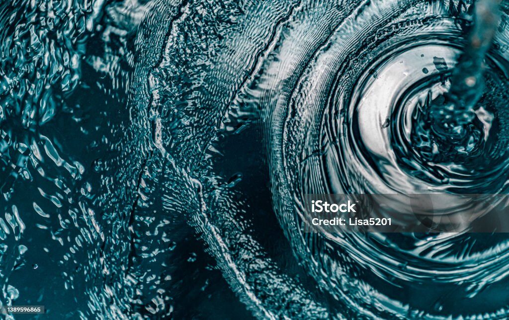 Close-up of water swirling in a glass bowl, creating ripples and textured reflections.